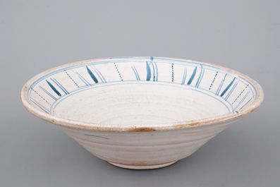A large Spanish blue and white faience bowl with a sun face, 19th C.